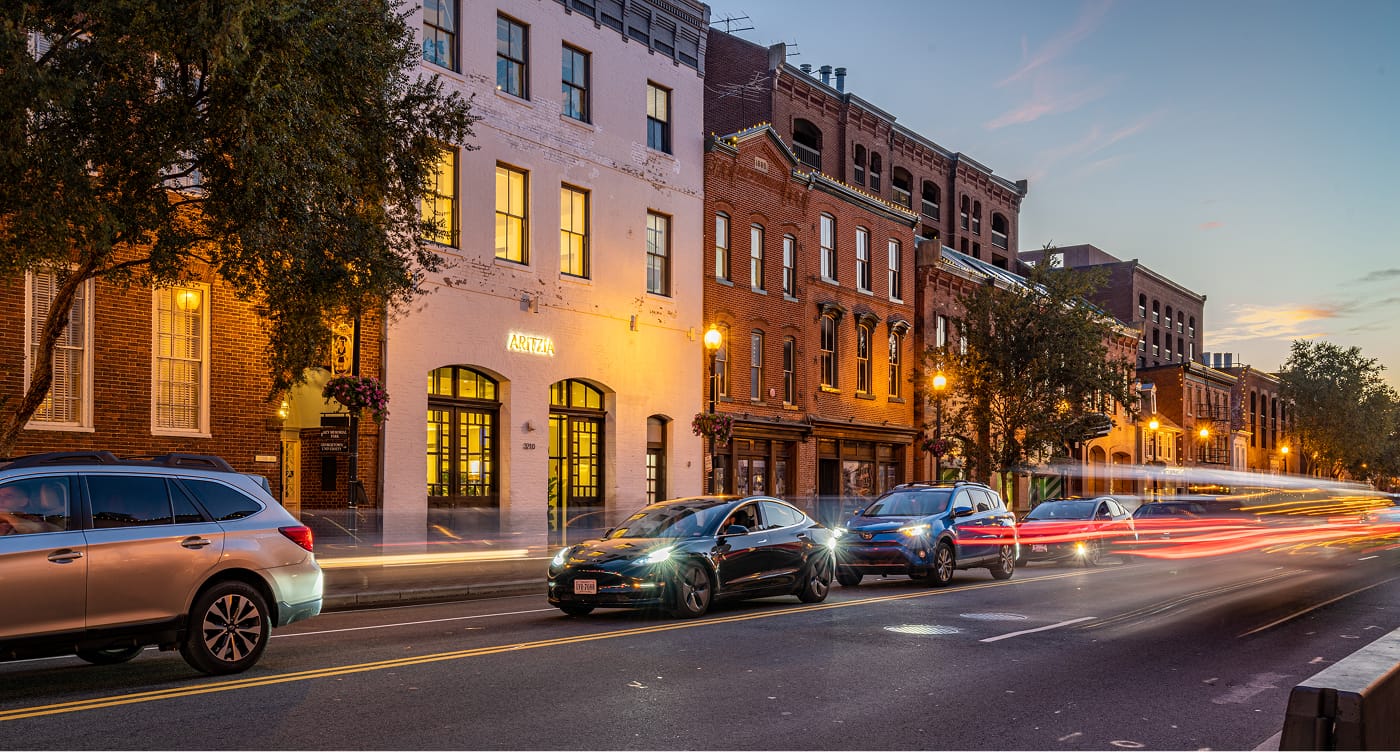 City street at dusk with cars and historic buildings.