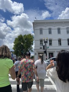 People walking on a city street toward a white building.