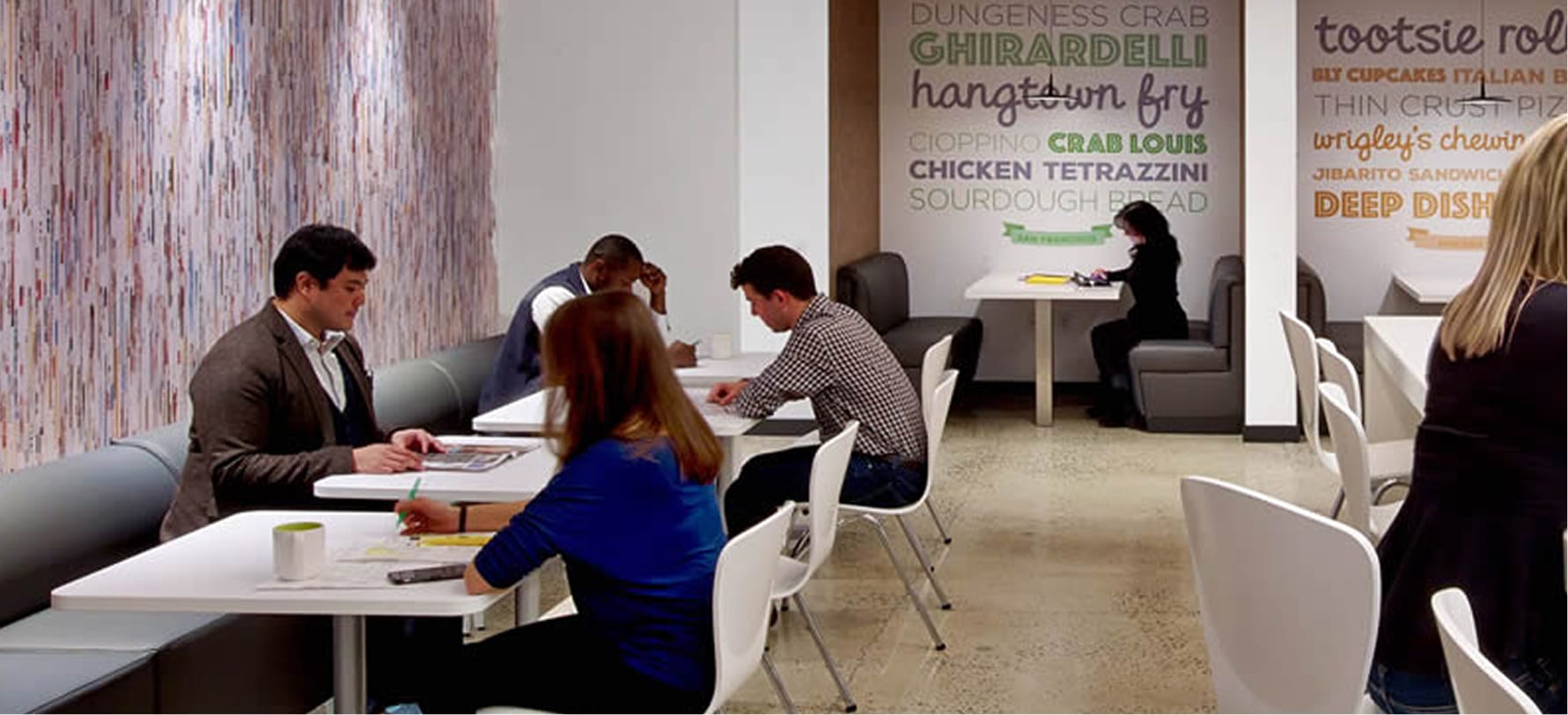 People working at tables in a modern office space.